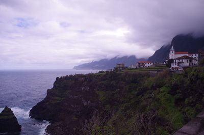 Scenic view of sea by buildings against sky
