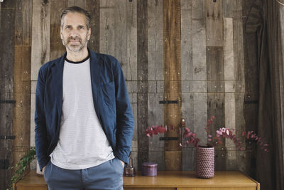 Portrait of confident businessman standing against wood paneling in portable office truck