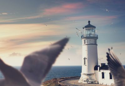 Lighthouse by sea against sky during sunset