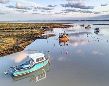 Fishing boats moored in lake against sky