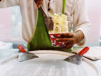 Midsection of man preparing ice cream with passion fruit at table.  