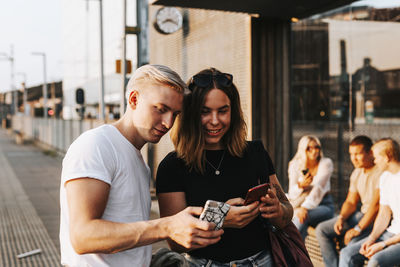 Young couple holding smart phone in city