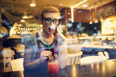 Portrait of surprised woman drinking cocktail at cafe