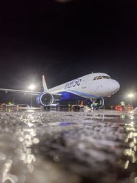 Illuminated airplane at airport against sky at night