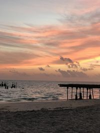 Silhouette pier on beach against sky during sunset