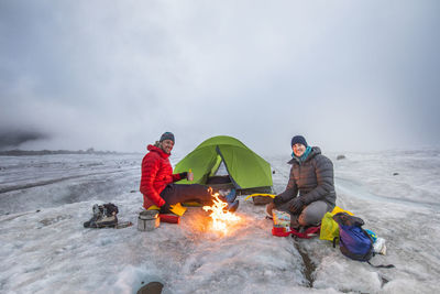 Teo mountaineers enjoys campfire while camping on a glacier.