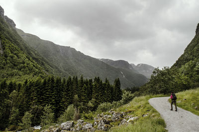 Rear view of man walking on mountain against sky