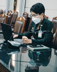 Rear view of woman using laptop at table