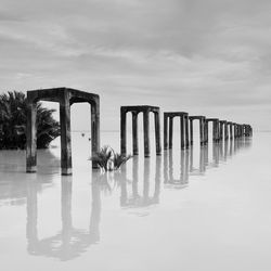 Wooden posts on beach against sky