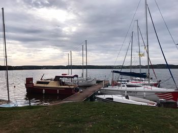 Sailboats moored at harbor against sky