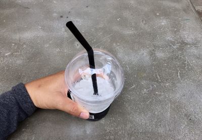 Cropped hand holding disposable cup on footpath