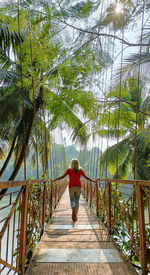 Rear view of woman walking on footbridge