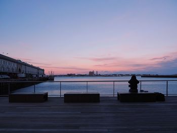 Silhouette man by sea against sky during sunset