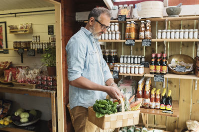 Mature man carrying basket while shopping in food store