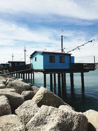 Pier over sea by buildings against sky