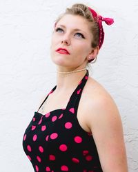 Portrait of young woman standing against wall