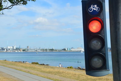 Traffic lights for bicycles by harbor in city against sky