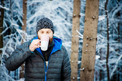 Portrait of young man with ice cream standing in winter