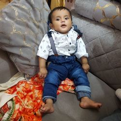 Portrait of baby boy sitting on sofa at home