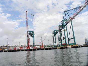 Cranes at commercial dock against sky