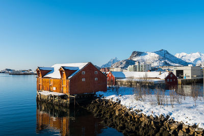 Houses by snowcapped mountains against clear sky