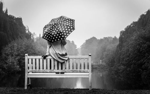 Low angle view of a woman in a light coat with a dotted umbrella. 