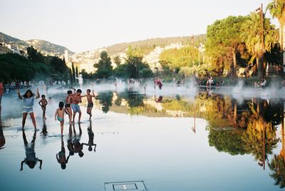 People on lake against clear sky