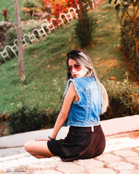 Young woman wearing sunglasses sitting outdoors