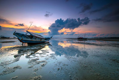 Boat moored in sea against sky during sunset