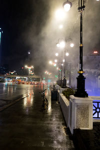 Illuminated street lights on road in city at night