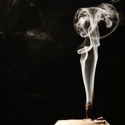 Close-up of incense burning against black background