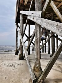 Wooden pier on beach against sky