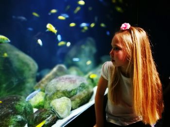 Girl with long blond hair sitting in aquarium