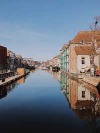 Canal amidst houses and buildings against blue sky