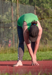 Sports woman stretching legs muscles and bend back before begin condition run on school stadium