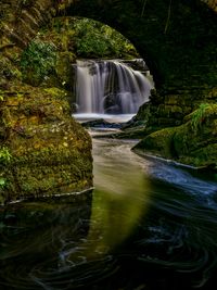 Beautiful little long exposure waterfall reflection under a stone bridge in killarney, ireland