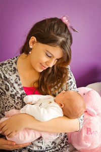 Smiling woman holding baby girl at home