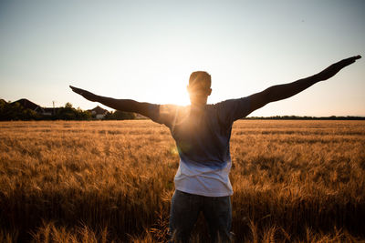 Man standing on field against sky during sunset