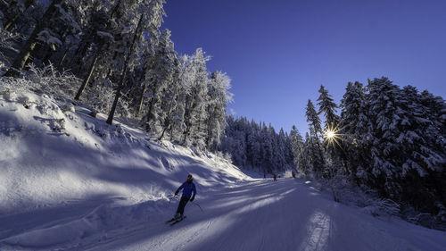 Man skiing on snow covered mountain against sky