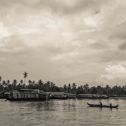 Boats in sea against cloudy sky