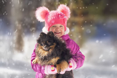 Portrait of child standing with dog during winter