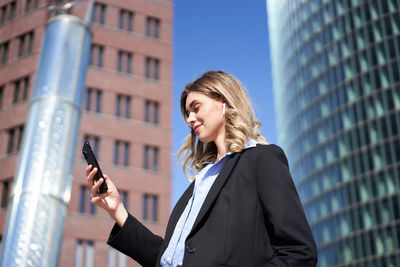 Portrait of young woman standing against buildings