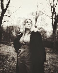 Young woman standing by bare tree