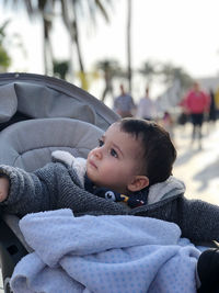 Little boy in his baby carriage, looking around serious on a winter day. with a blanket on her lap. 