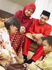 Parents looking at children playing game at home