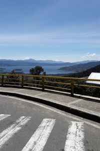 Road by railing against sky