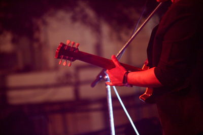 Midsection of man playing guitar at music concert