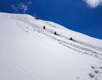 People skiing on snow covered mountain against sky