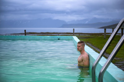 Man relaxing in swimming pool against sea