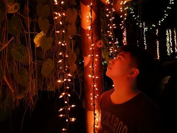 Boy looking at illuminated christmas lights at night